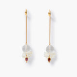 A pair of gold dangle earrings with white mother-of-pearl bow charms with faceted clear quartz spheres and small bezeled lens-shaped garnet gemstones, shown on a clean white background.