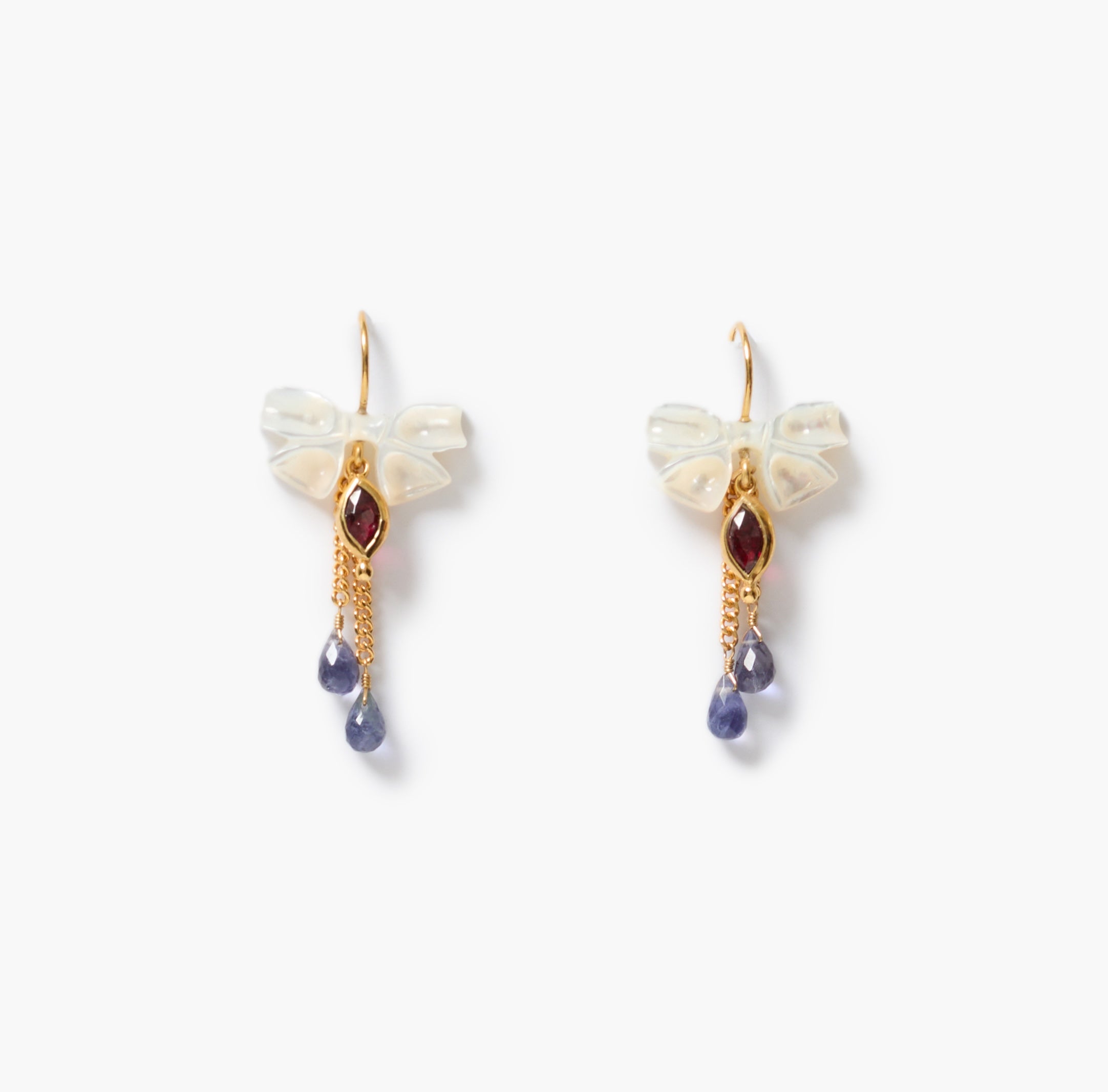 A pair of gold-tone dangle earrings featuring a small white shell bow, a lens-shaped garnet gemstone, and two dangling blue teardrop beads, set against a plain white background.