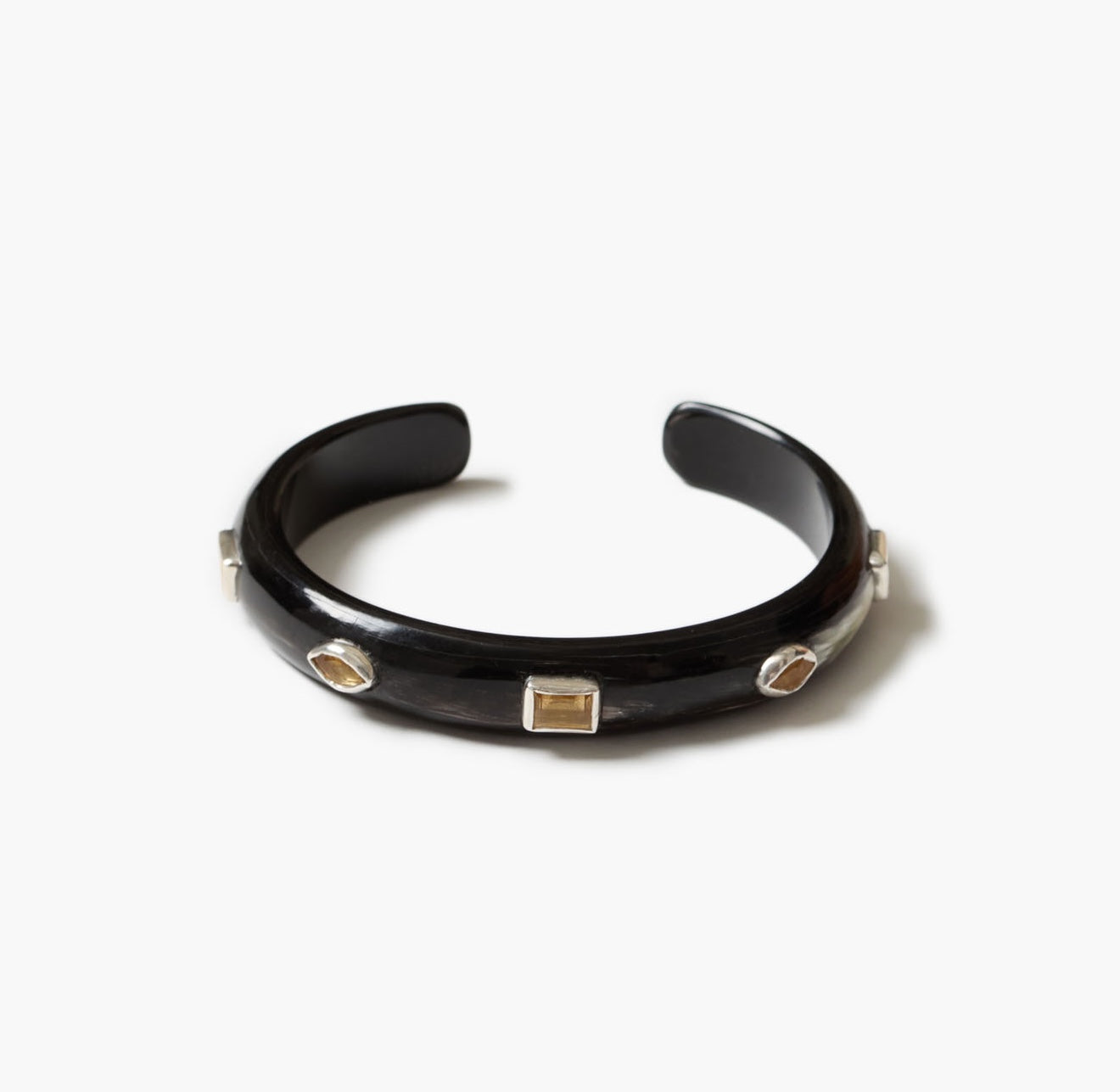 A glossy black  horn open cuff bracelet with three small geometric inset stones in silver-toned settings